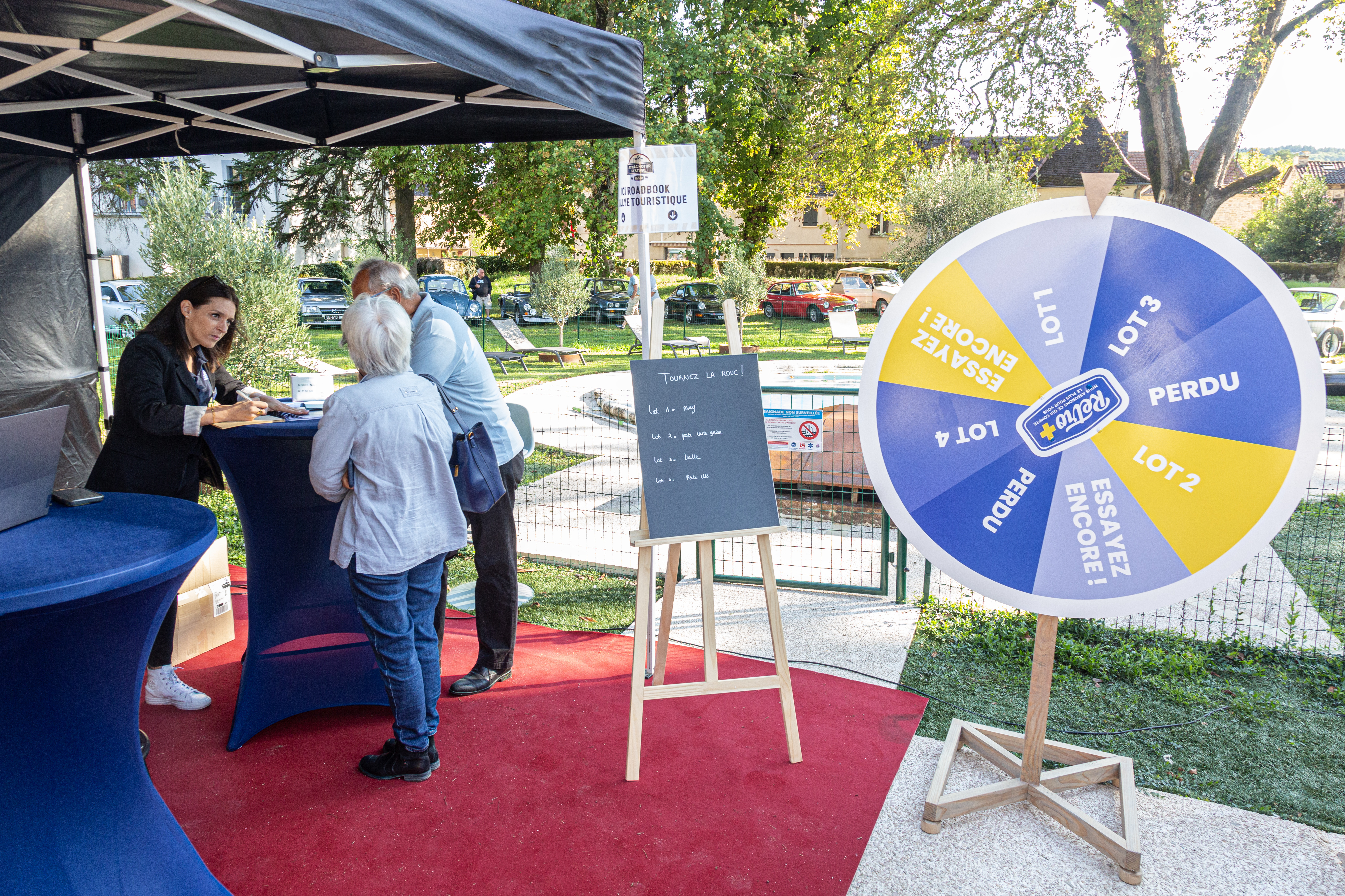 Conseillère avec clients et roue de la chance, stand Rétro+, Aynac motor festival